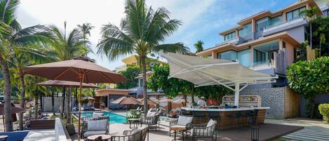 A poolside area with lounge chairs, umbrellas, and a bar.