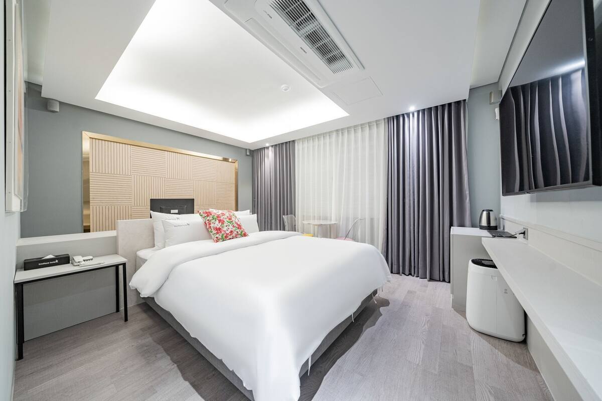 Una camera d'albergo moderna con un letto, un comodino, una lampada e uno specchio grande.
