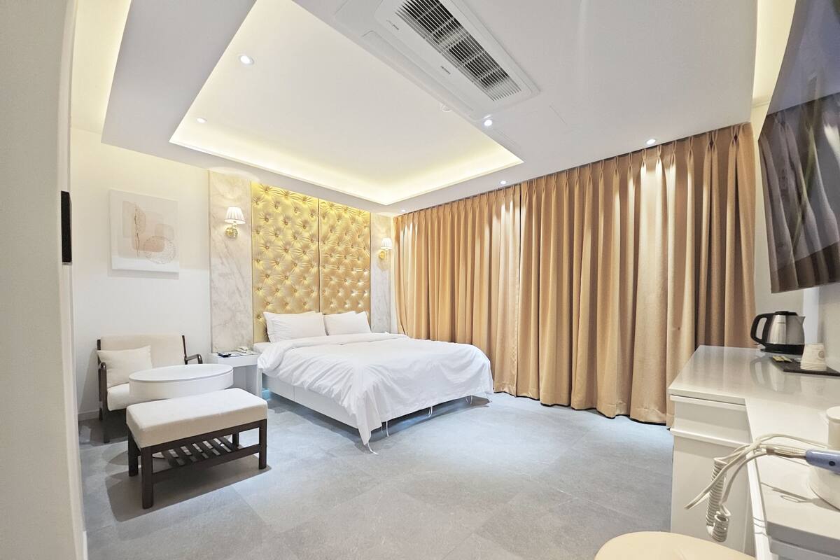 Una moderna camera d'hotel con un letto, un comodino, una sedia e una scrivania con un bollitore.
