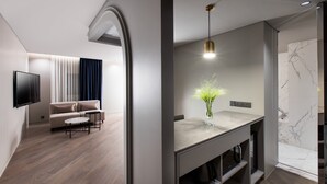 Una sala de estar moderna con un sofá, televisor y un comedor con protector de encimera de mármol.