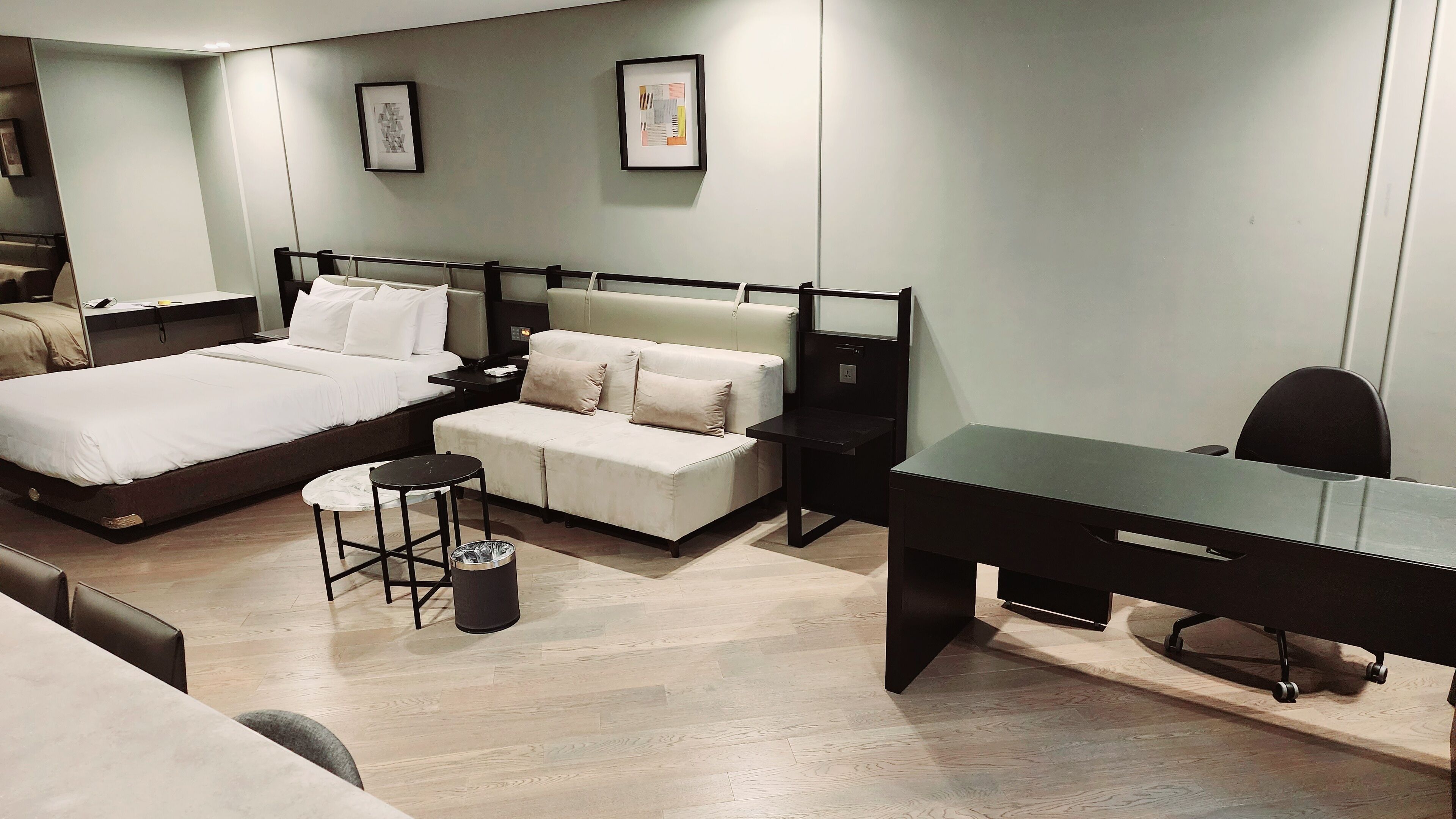 A modern hotel room with a bed, a sofa, a desk, and a chair.