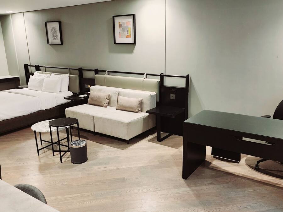 A modern hotel room with a bed, a sofa, a desk, and a chair.