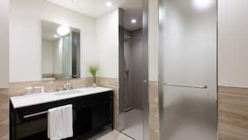 Un baño moderno con cabina de ducha de vidrio, un espejo grande y un mueble de tocador negro con una toalla colgada.