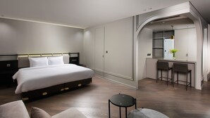 Una habitación de hotel moderna con una cama grande, un escritorio con dos sillas, una mesita y un espejo.