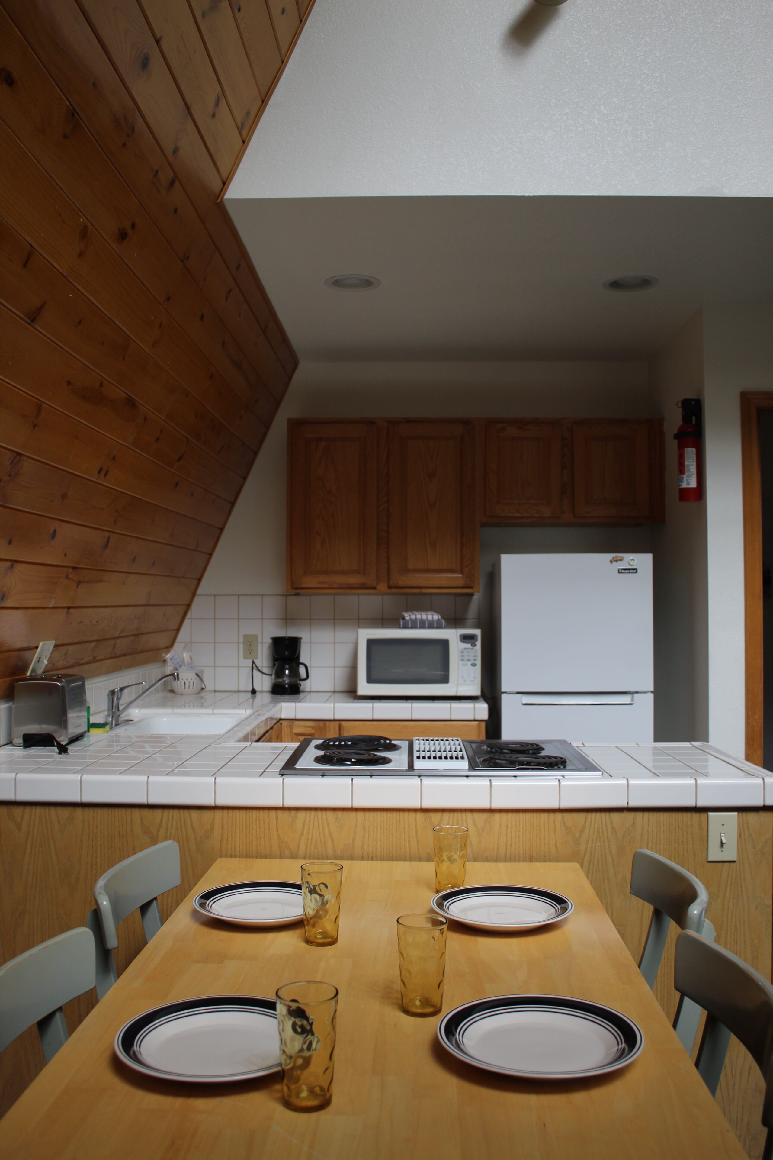 Una cocina con armarios de madera, microondas, estufa y refrigerador.