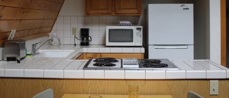 A kitchen with wooden cabinets, a microwave, a stove, and a refrigerator.