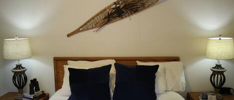 A neatly made bed with a wooden headboard, two bedside tables with lamps, and a wall-mounted decorative piece.