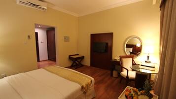 Habitación de hotel con cama, escritorio con lámpara, silla, televisor y frutero.