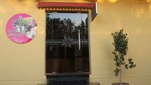 A massage center entrance with a signboard, a potted plant, and a window with a decorative element. - Al Maha Residence RAK (Ras Al Khaimah)