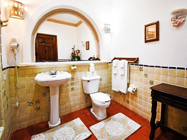 Een badkamer met een wastafel op een voetstuk, toilet en een wastafelmeubel met spiegel.