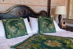 Una cama con dos almohadones decorativos y un plaid verde bordado.