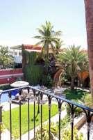 A courtyard with outdoor seating, palm trees, and a pool.