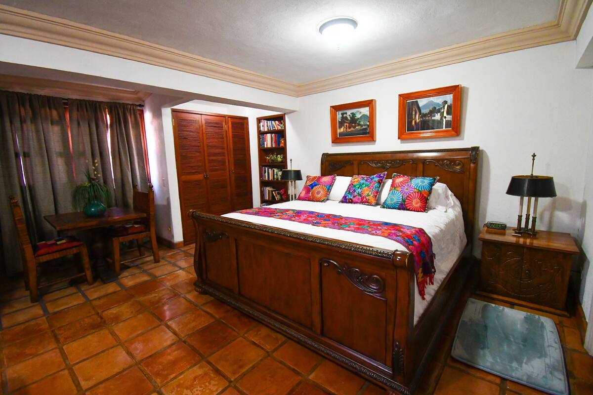 Un dormitorio con una cama de madera, un escritorio, una estantería y un armario.
