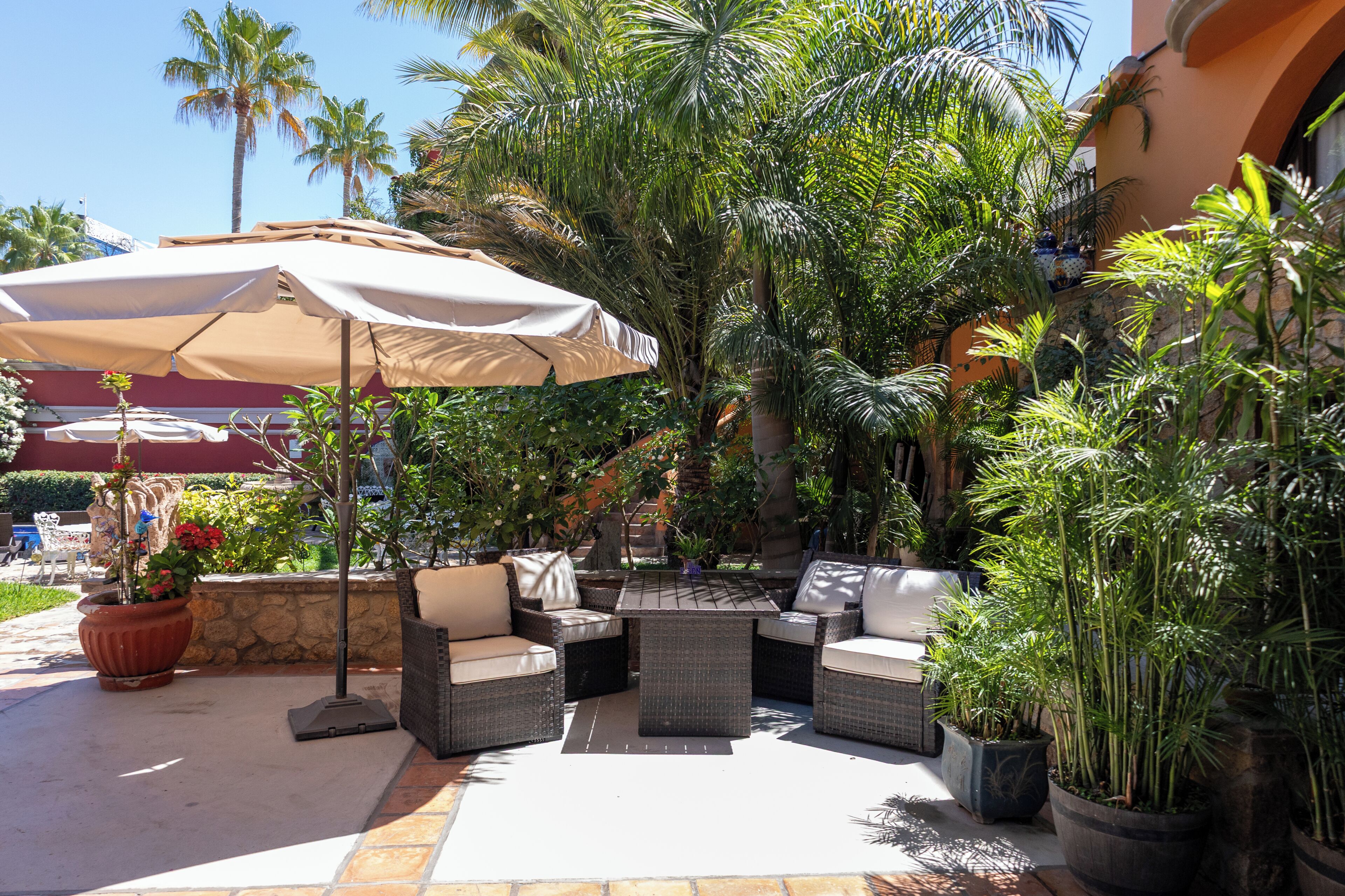 An outdoor patio with wicker furniture, a table, and a large umbrella.