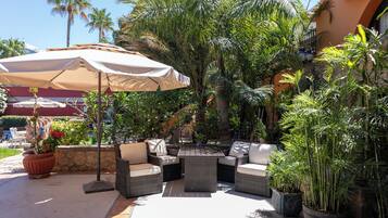 An outdoor patio with wicker furniture, a table, and a large umbrella.