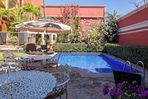 A pool area with a blue pool, outdoor furniture, and a variety of plants and flowers. - Collection O Casa Bella Hotel Boutique, Cabo San Lucas (Cabo San Lucas)