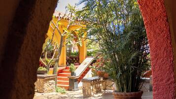 Un arco de entrada da a un patio con una planta en maceta, escalones de piedra y suelo de baldosas.