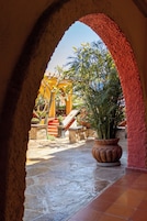 Un arco de entrada da a un patio con una planta en maceta, escalones de piedra y suelo de baldosas.