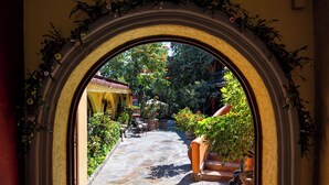 An arched doorway leading to a courtyard with stone flooring, potted plants, and outdoor seating.