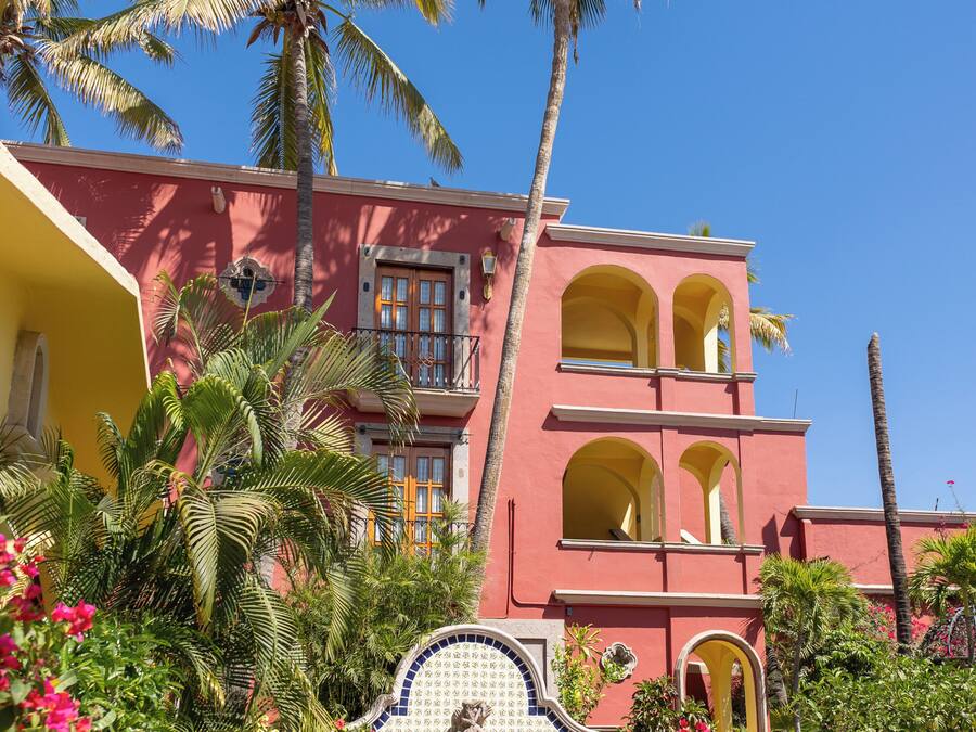 A two-story building with balconies and a pool area with lounge chairs.