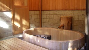 Een houten interieur met een bubbelbad, houten vloeren en een betegelde muur.