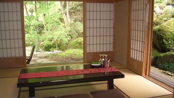 Ein traditioneller japanischer Raum mit Tatami-Böden, einem niedrigen Tisch mit rotem Läufer und Shoji-Schirmwänden.