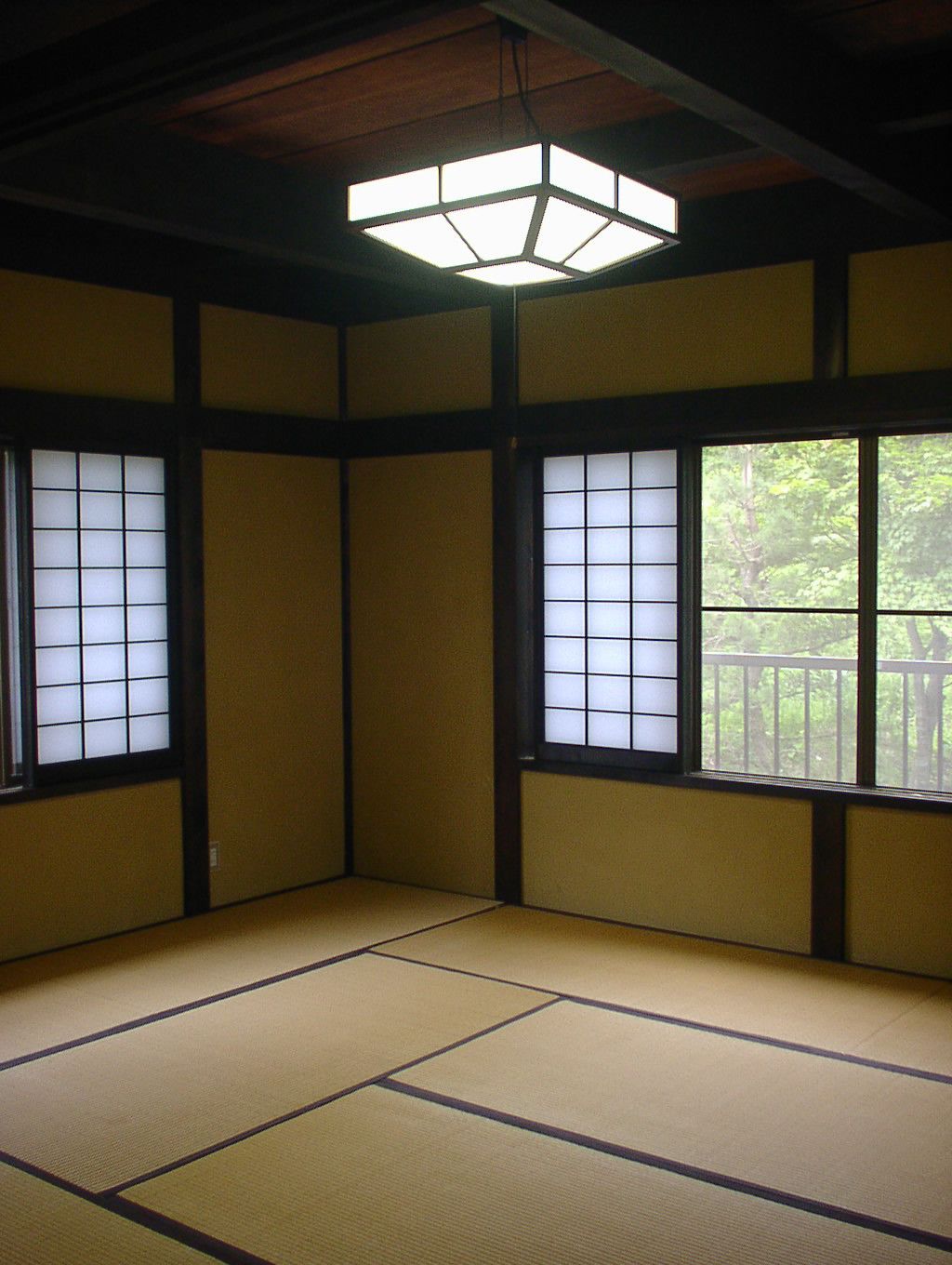 A traditional Japanese room with tatami flooring, shoji screens, and a hanging paper lantern.