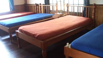 A room with three wooden beds arranged in a row, each with a wooden headboard and a mattress.