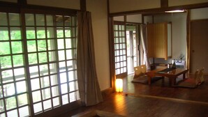 Een traditionele Japanse kamer met tatami vloeren, een lage houten tafel en schuifdeuren die leiden naar een keuken.