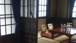 Een traditionele Japanse kamer met tatami vloerbedekking, een lage houten tafel en een hangende lantaarn.