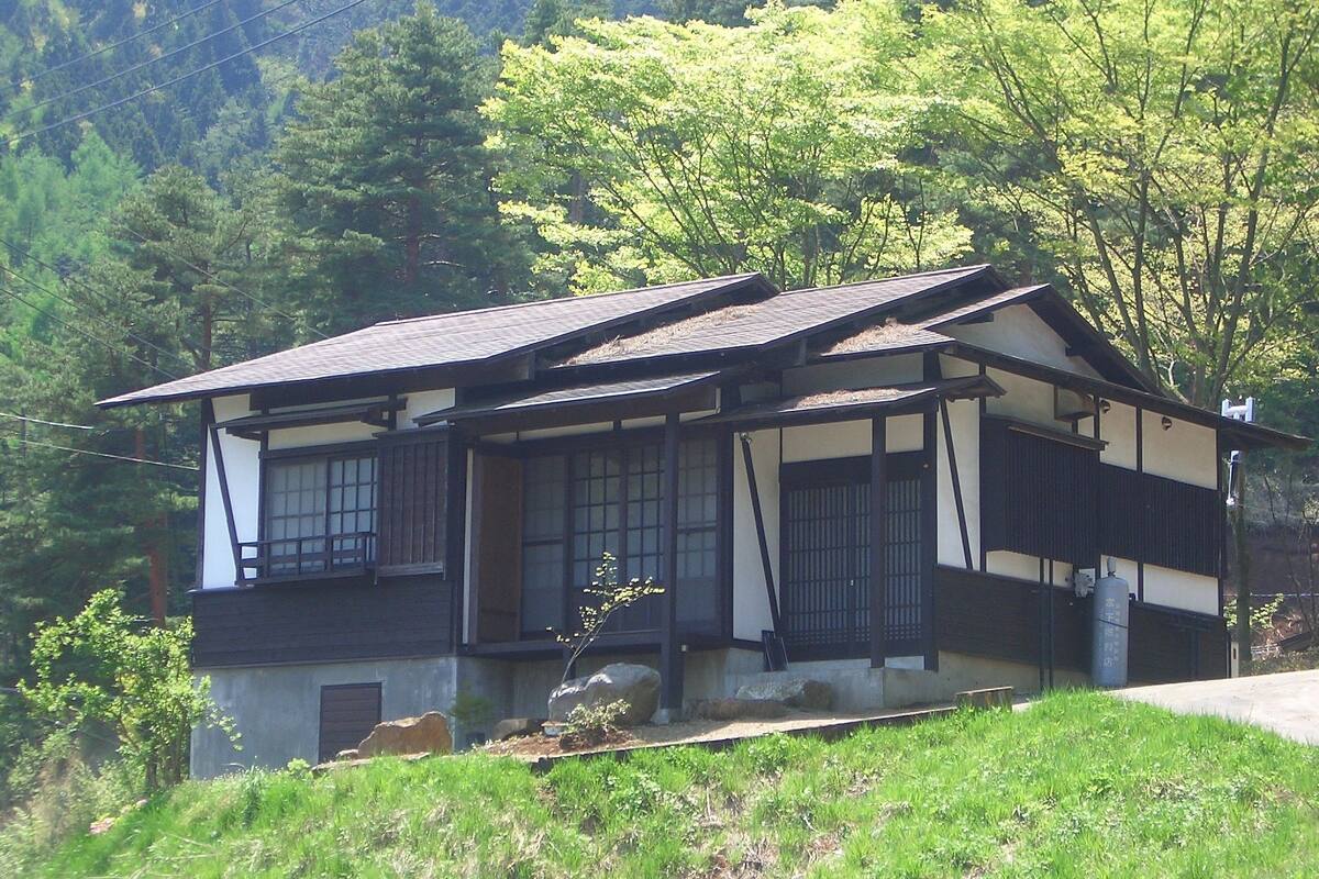 Une maison traditionnelle japonaise, caractérisée par un toit en pente, des poutres en bois et des fondations en pierre.
