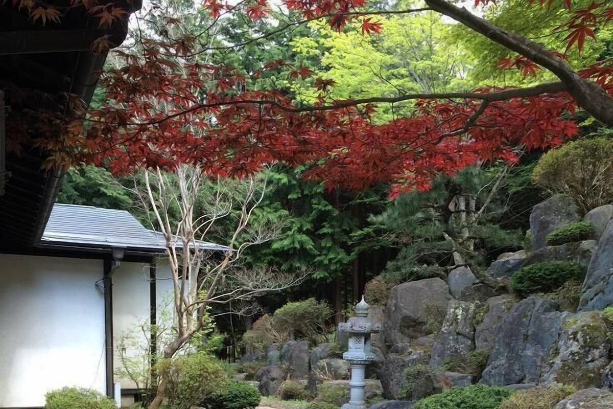 Un jardin agrémenté de chemins en pierre, de bancs en bois et d’un élément décoratif aquatique traditionnel japonais.