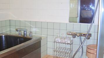 Un baño con suelo de madera, un lavamanos grande, una ducha y un espejo.