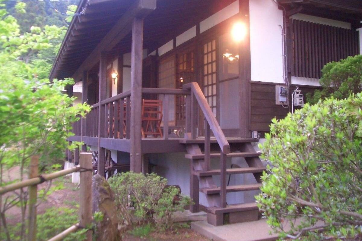 Un bâtiment traditionnel en bois, doté d’un porche et d’un escalier menant à une porte.