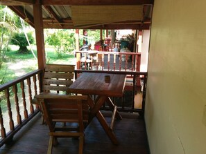 A wooden deck with a table and chairs, overlooking a garden with a pathway and trees. - Paradise Garden Resort (Ko Pha-ngan)
