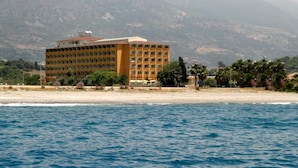 A hotel with a modern design, located near a beach with a view of mountains in the background. - Sunshine Hotel (Alanya)