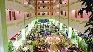 A multi-level atrium with a central decorative structure, multiple seating areas, and indoor plants. - Sunshine Hotel (Alanya)