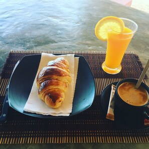 A croissant on a plate, a glass of orange juice, and a cup of coffee on a table. - Papillon Bungalows (Ko Pha-ngan)