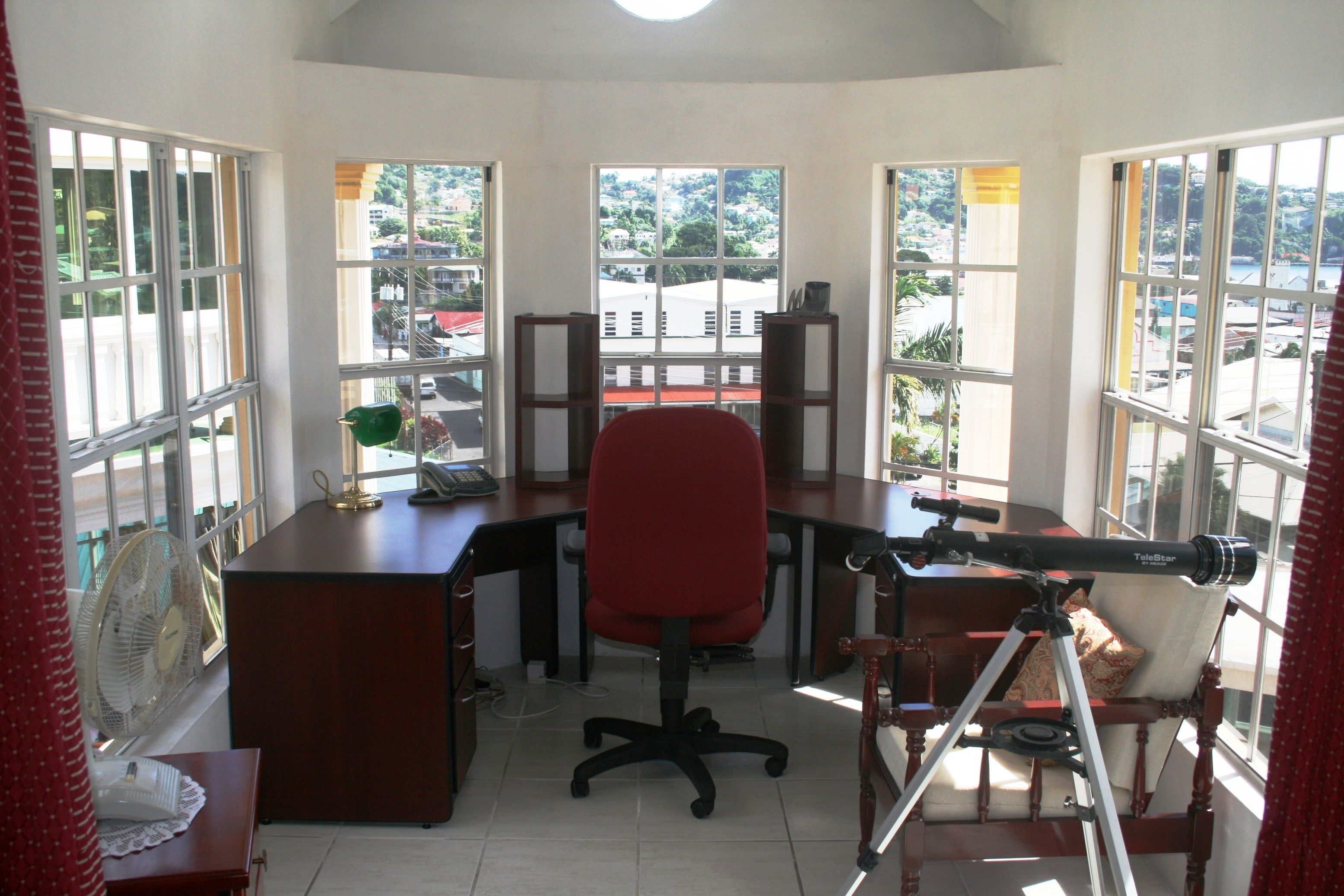 A room with a desk, office chair, and a telescope.
