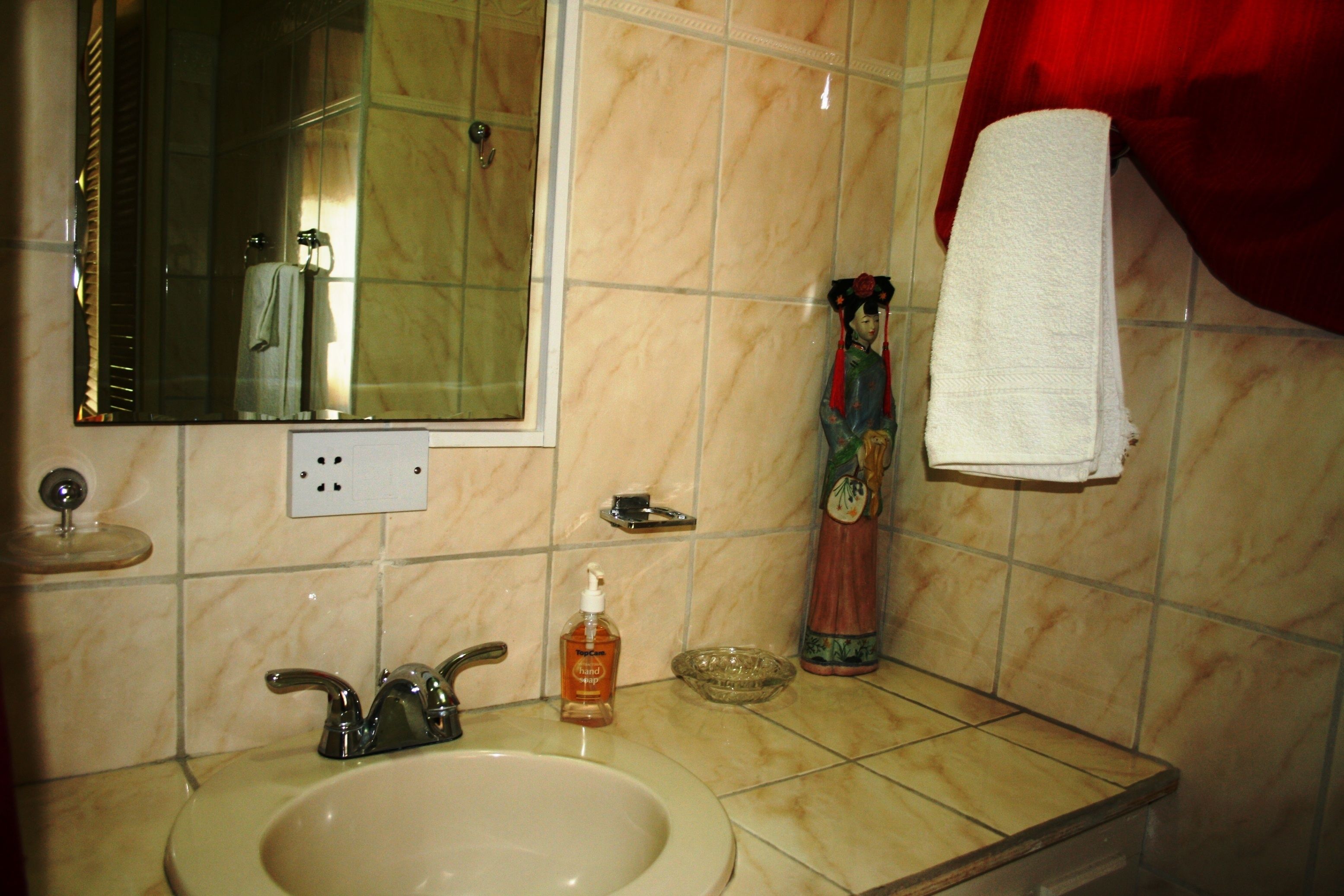 A bathroom with a sink, mirror, and a decorative statue.