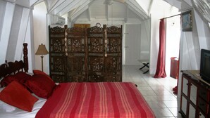 A bedroom with a bed, a wooden wardrobe, a ceiling fan, and a television. - Fairview Guest House (Kingstown)