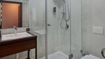 Ein modernes Badezimmer mit einer Duschkabine aus Glas, einem Holzbadezimmermöbel und einer weißen Toilette.