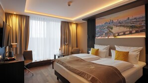 Habitación de hotel con una cama grande, un escritorio, una silla y vistas a la ciudad.