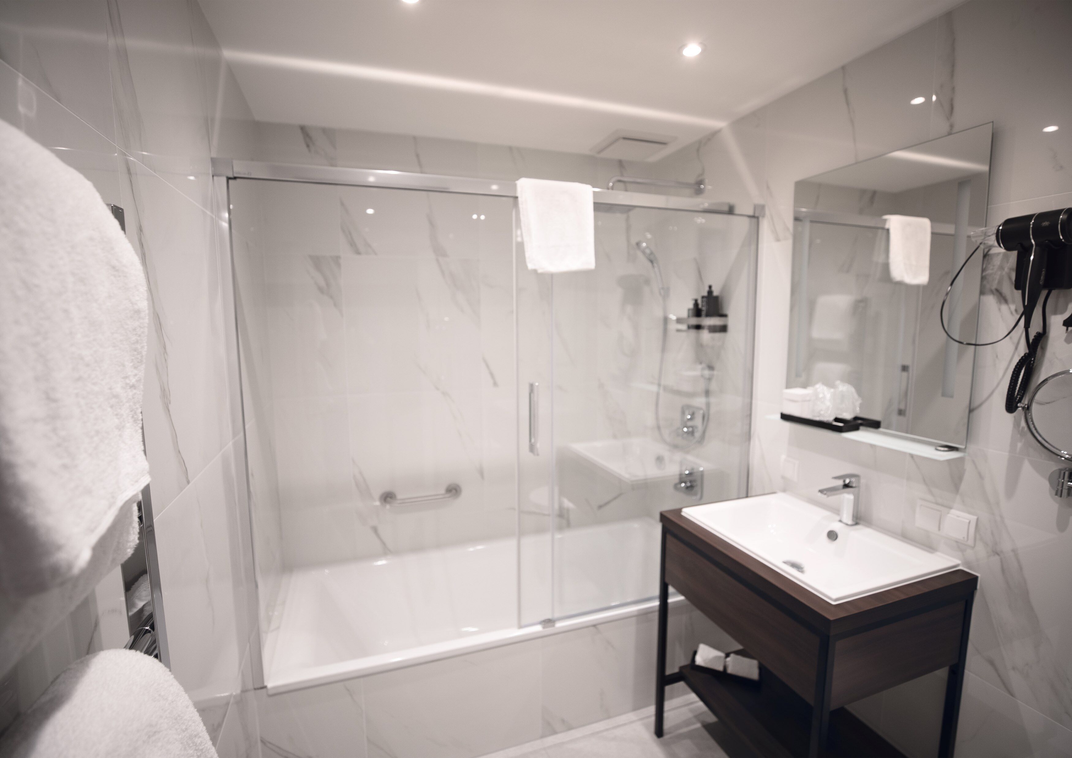A modern bathroom with a glass-enclosed shower, a white sink, and a large mirror.