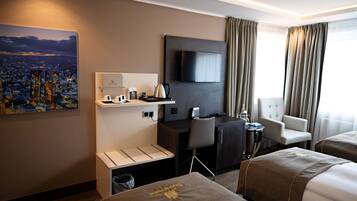 A hotel room with a bed, a desk, a chair, a TV, and a painting of a cityscape.
