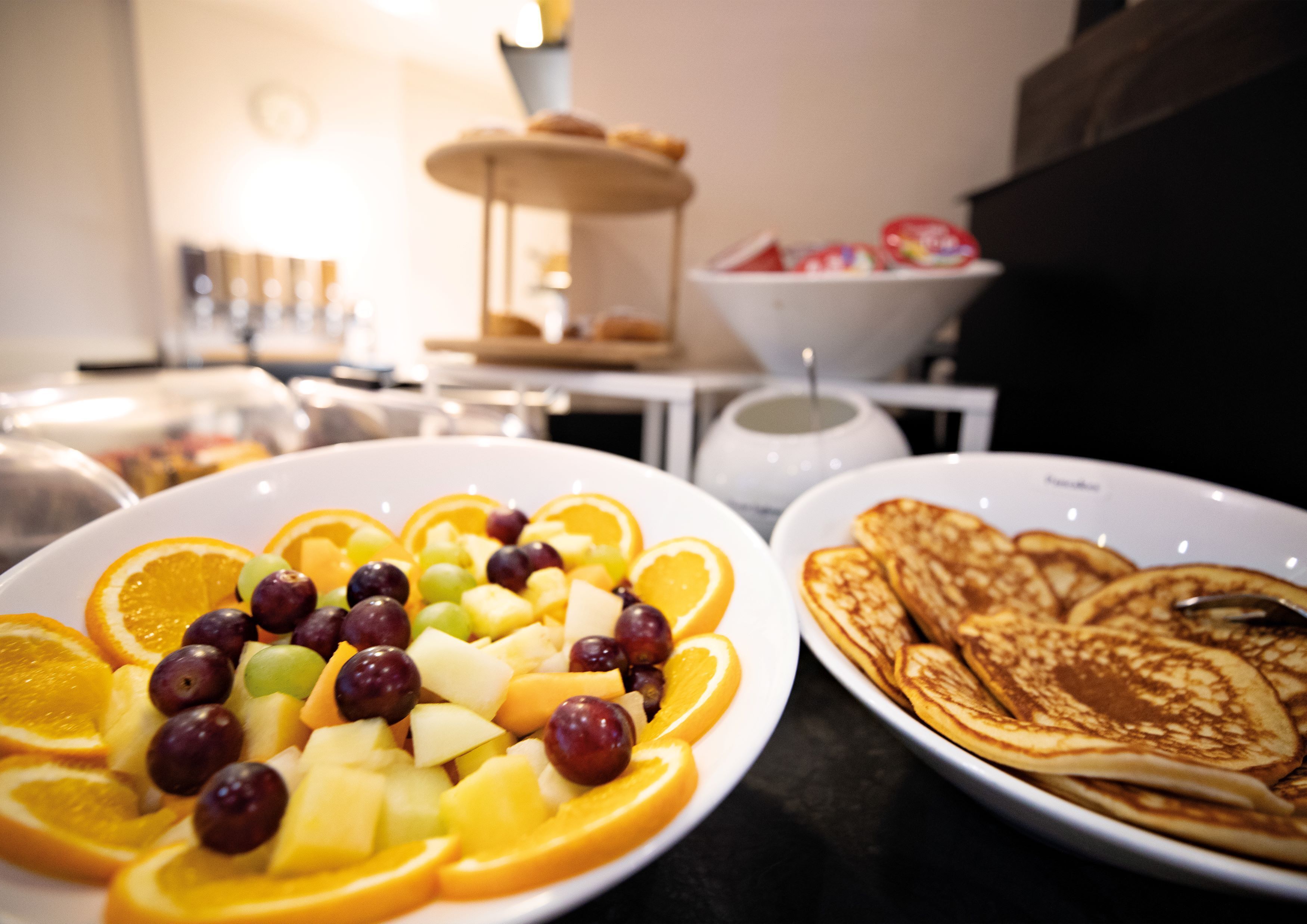 A breakfast setting with fruit and pancakes on plates.