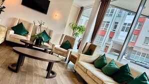 Una sala de estar moderna con un sofá color beige, una mesa de centro redonda y un ventanal con vistas a edificios.