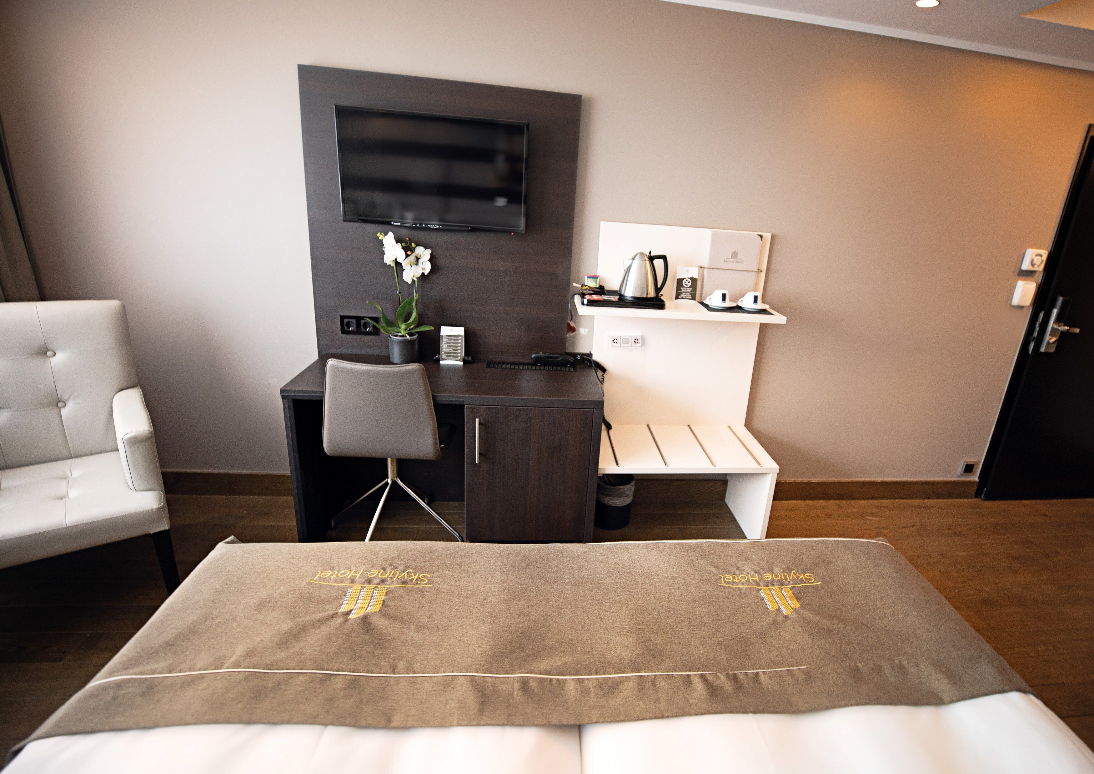 Ein Hotelzimmer mit einem Bett, einem Schreibtisch, einem Stuhl, einem Fernseher und einem kleinen Regal mit Pflegeprodukten.