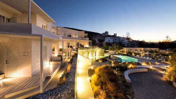 Un resort moderno con piscina, zona de estar al aire libre y un sendero bien iluminado.