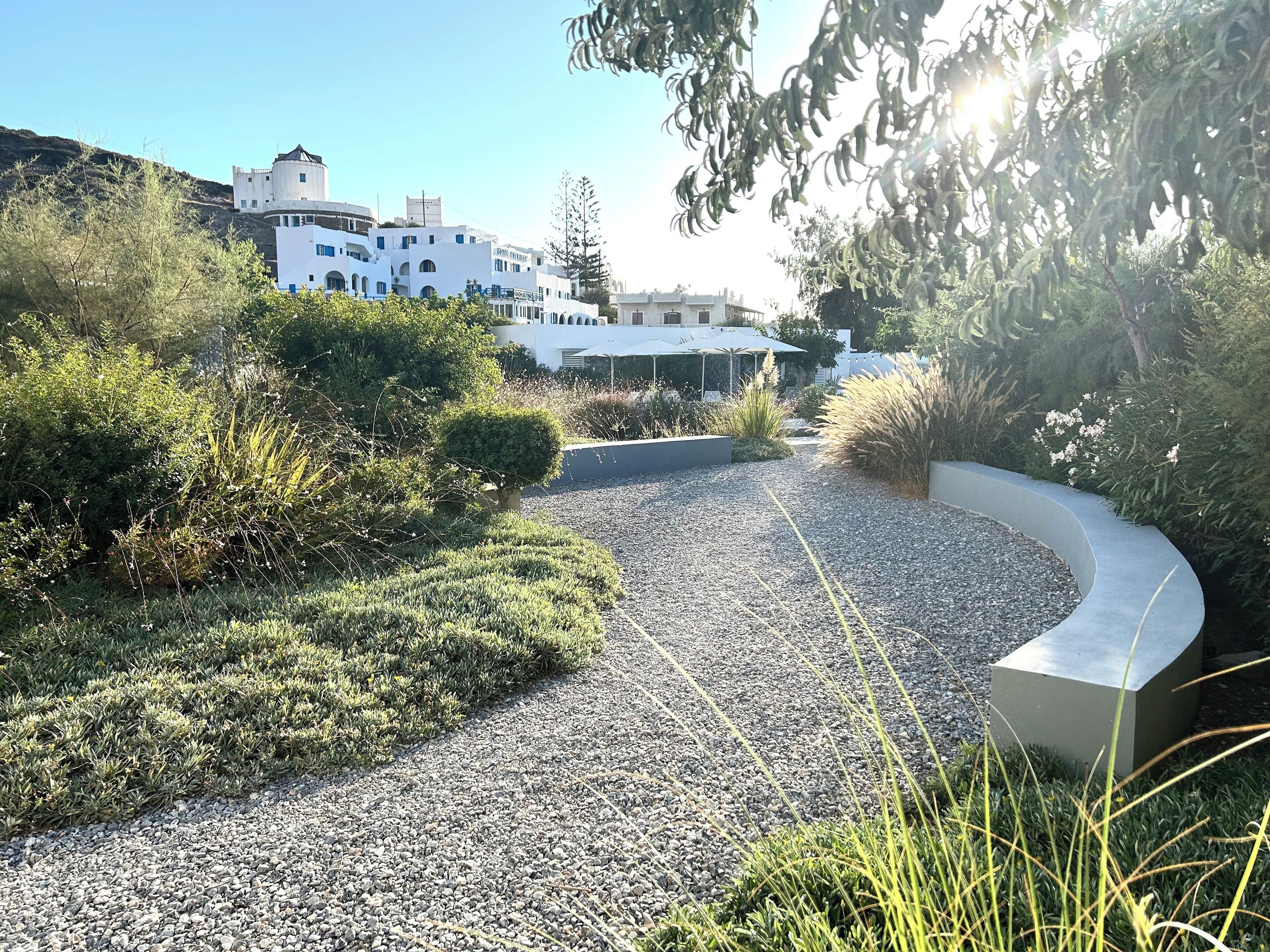 A gravel pathway leading to a modern building with white walls and multiple windows.